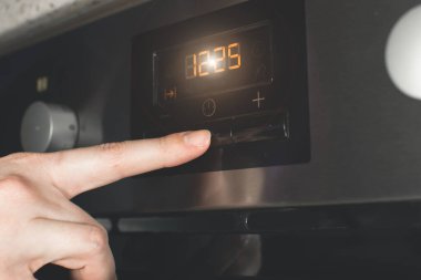 Kadın modern elektrikli fırını mükemmel yemek hazırlamak için zamanlayıcıyla ayarlıyor..