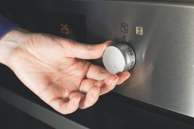 Kadın modern elektrikli fırını mükemmel yemek hazırlamak için zamanlayıcıyla ayarlıyor..