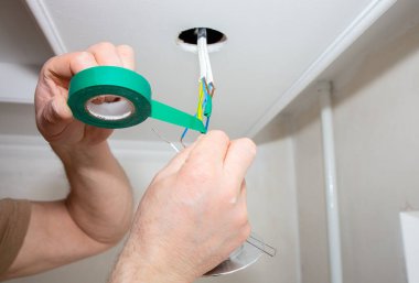 Adam elinde yapışkan bant tutuyor. Ampul için elektrik yalıtkan. Bakım onarımı dairede işe yarıyor. İçerideki restorasyon.