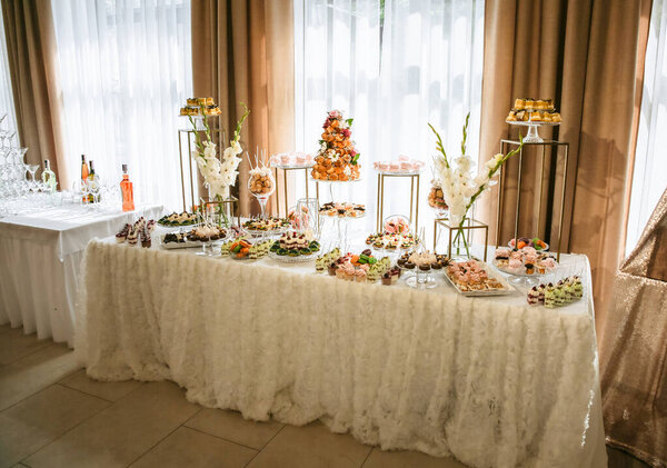 Candy bar at the wedding reception. Cupcakes and sweets. Beautiful decorations. White flowers. Delicious desserts.