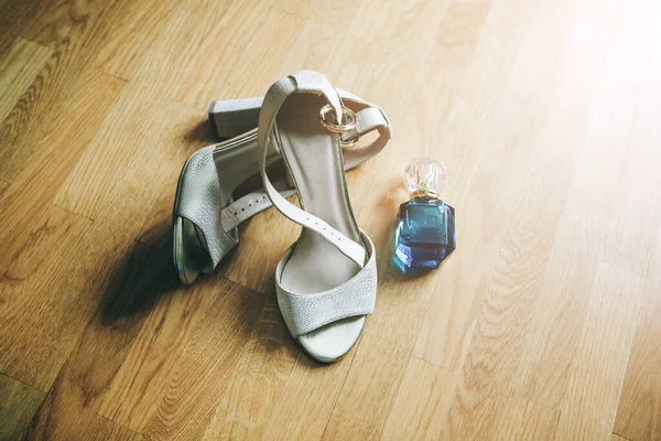 新娘的鞋子站在木地板上 香水在附近 婚礼上午的细节 — 图库照片