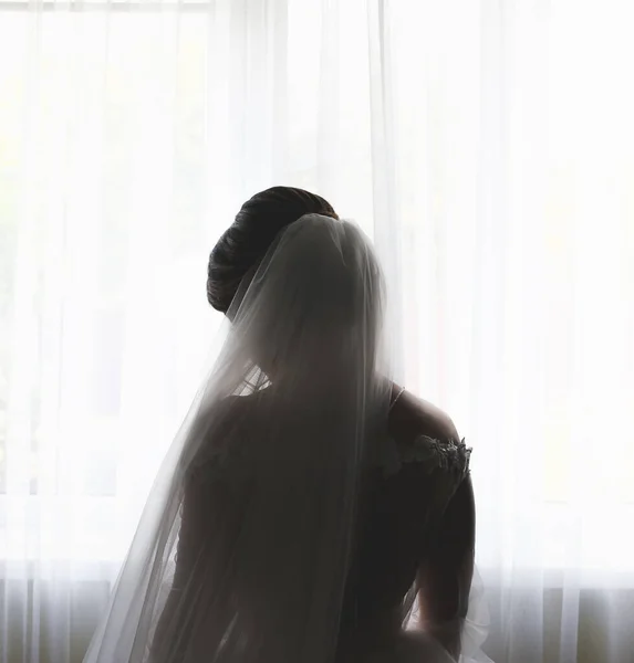 花嫁は窓の近くに立っている 美しい長袖のドレス レースクロス 結婚式の朝の詳細 白黒写真 — ストック写真