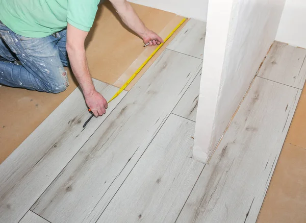 Worker making laminate flooring in apartment. Maintenance repair renovation. Wooden parquet planks indoors.