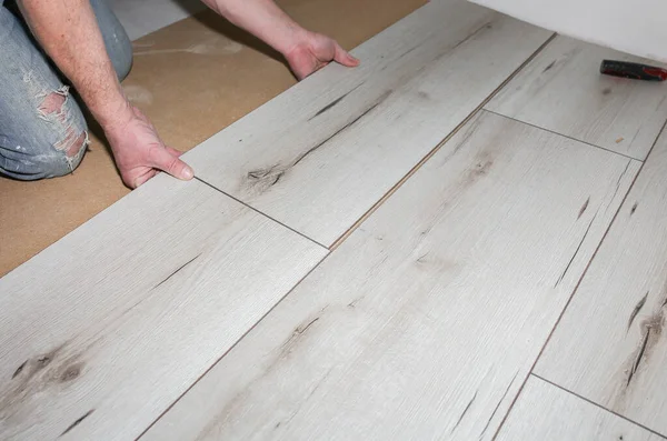 stock image Worker making laminate flooring in apartment. Maintenance repair renovation. Wooden parquet planks indoors.