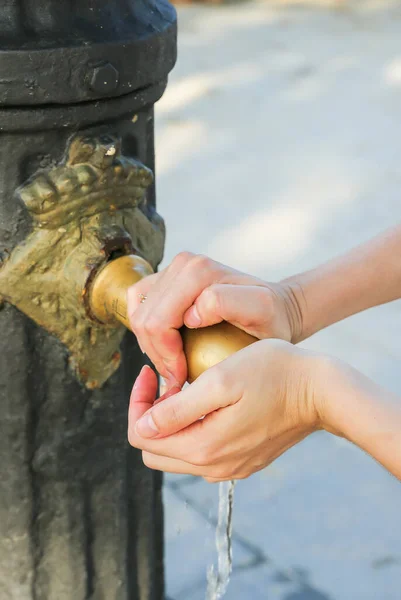 stock image Girl is washing hands in the old medieval tap in the street. Tourist in the hot city.