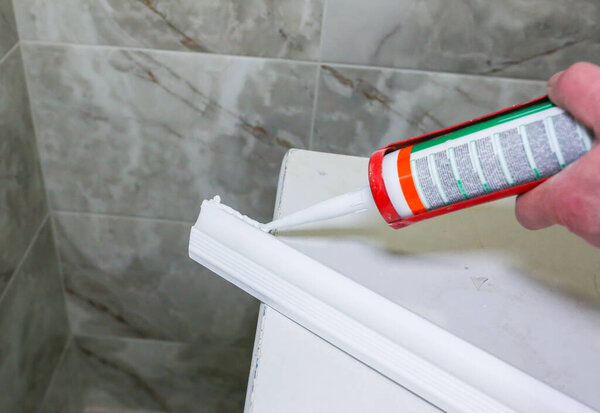 Человек кладет клей на гипсокартон. Ремонтные работы в квартире. Реставрация в помещении. Дриволновая панель.