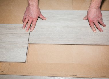 İşçi dairede döşeme kaplaması yapıyor. Onarım onarımı. Ahşap parke kalasları içeride..