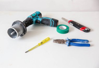Masada duran tornavida ve yapıştırıcı bant. Apartmanda bakım onarımı için bıçak ve elektrikli matkap kullanılıyor..