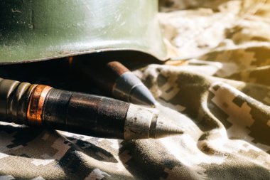 Haki kamuflaj arka planında kurşunlar ve miğfer. Ödünç verme ve ordu konsepti. Silah ve mühimmat satışı. Askeri sanayi, savaş, küresel silah ticareti.