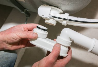 Banyo kurulumu. İşçi hortum borusuyla drenaj yapıyor. Dairede bakım onarımı var. Yenileme işlemi.