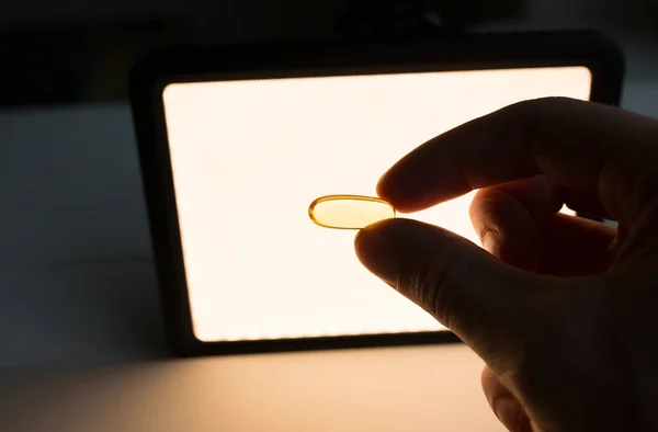 stock image Omega 3 pills in man's hand on light lamp background. Healthy diet supplements. Fish oils for vegans food.