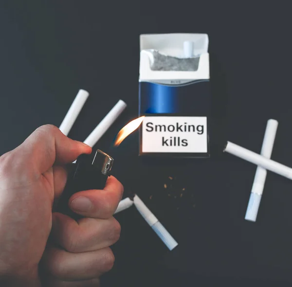 香烟包装上有吸烟致人死亡的标志 很危险的习惯对健康有害 男人手握打火机 — 图库照片