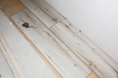 Dairenin döşemesini cilalayın. Bakım onarımı yenileme işidir. Kapalı alanda ahşap parke döşeme onarımı. Mezurayı ve kalemi ölç.