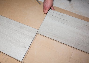 İşçi dairede döşeme kaplaması yapıyor. Onarım onarımı. Ahşap parke kalasları içeride..