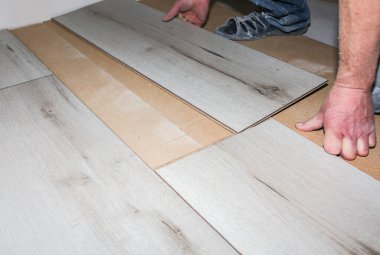 İşçi dairede döşeme kaplaması yapıyor. Onarım onarımı. Ahşap parke kalasları içeride..