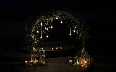 Düğün töreninde beyaz çiçek kemeri. Açık hava dekorasyonu. Romantik köy tarzı. Akşamları lambalar.