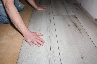 İşçi dairede döşeme kaplaması yapıyor. Onarım onarımı. Ahşap parke kalasları içeride..