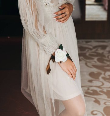 Gelin dizlerinin üstünde el ele tutuşuyor. Güzel beyaz manikür. Nişan yüzükleri parmaklarda. Düğün günü detayları. Zarif aksesuarlar..