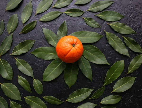 Siyah arka planda yeşil yapraklı turuncu. Sağlıklı bir yaşam tarzı fotoğrafı. Güzel duvar kağıdı. Vejetaryen ve vejetaryen kavramı. Doğadan gelen vitaminler.