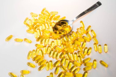 Beyaz ahşap arka planda kaşıkta Omega 3 hapları. Sağlıklı beslenme takviyeleri. Vejetaryen yemeği için balık yağı..