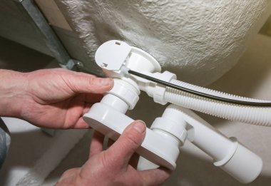 Banyo kurulumu. İşçi hortum borusuyla drenaj yapıyor. Dairede bakım onarımı var. Yenileme işlemi.