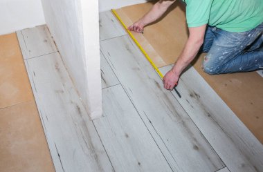 İşçi dairede döşeme kaplaması yapıyor. Onarım onarımı. Ahşap parke kalasları içeride..