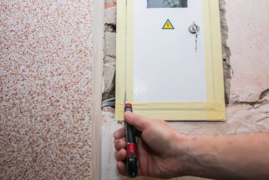 İşçi boyacı bandını elektrik paneline yapıştırıyor. Bakım onarımı dairede tadilat yapıyor. İçerideki restorasyon.