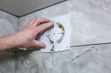 Adam banyodaki vantilatör vantilatörünü takıyor. Restorasyon süreci.