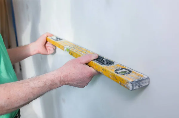 stock image Restoration with bubble level indoors. Man is holding a spirit level in hands. Maintenance repair works renovation in the flat.