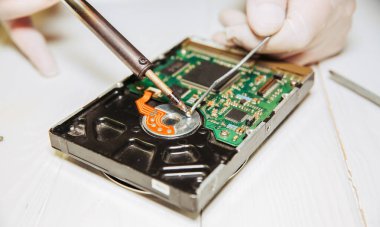 Adam sabit diski tamir ediyor. Eski kişisel bilgisayarın içinde. Kırık bilgisayar. Lehim demiri ellerinde..