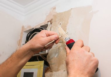 İşçi, çizgi işçisinin pensesiyle kablo kesiyor. Bakım onarımı dairede tadilat yapıyor. İçerideki restorasyon.