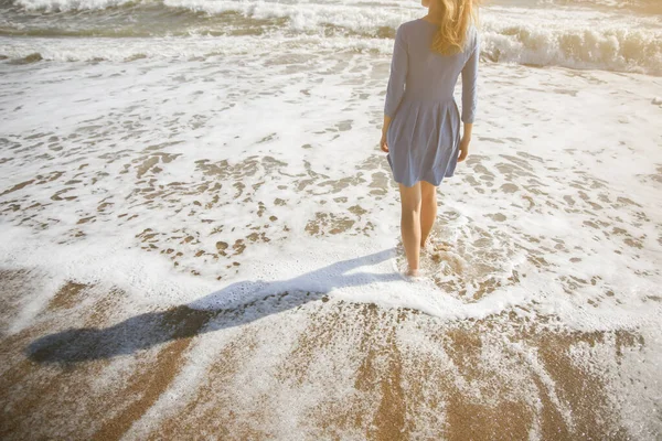 青いドレスの美しい少女は ビーチを歩いている 素晴らしい夏の写真 海の近くの女性 休日の旅行の概念 足が細い 暖かい海の水 — ストック写真