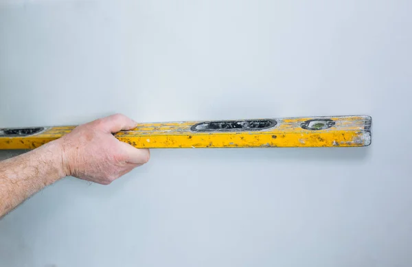 stock image Restoration with bubble level indoors. Man is holding a spirit level in hands. Maintenance repair works renovation in the flat.