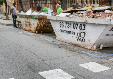 BARCELONA, İspanya - 15 Ekim 2018: Barcelona 'daki Sant Pau hastanesi yakınlarında yol bakım çalışmaları. Sokaktaki işçiler. Metal kutularda çöp var..