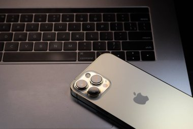 KYIV, UKRAINE - 20 Ekim 2023: Modern akıllı telefon Apple iPhone 15 Pro ve Apple Macbook Pro laptop. Cupertino teknoloji aletleri. Marka logosu adı.