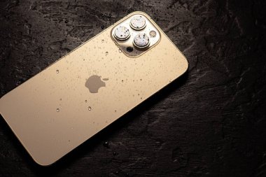 KYIV, UKRAINE - 20 Ekim 2023: Modern akıllı telefon Apple iPhone 15 Pro ve siyah zemin üzerinde su damlaları. Suya dayanıklı modern teknoloji.
