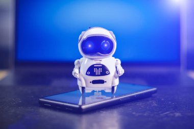 Akıllı telefondan beyaz arka planı olan çok küçük bir robot. Geleceğin teknolojisi. Gelişim için iş yardımcısıyım. Çevrimiçi yardımcı, sohbet bot.