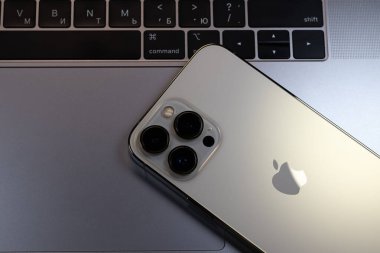 KYIV, UKRAINE - 20 Ekim 2023: Modern akıllı telefon Apple iPhone 15 Pro ve Apple Macbook Pro laptop. Cupertino teknoloji aletleri. Marka logosu adı.
