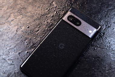 KYIV, UKRAINE - 03 Ekim 2023: Modern akıllı telefon Google Pikseli ve siyah zemin üzerinde su damlaları. Suya dayanıklı modern teknoloji.