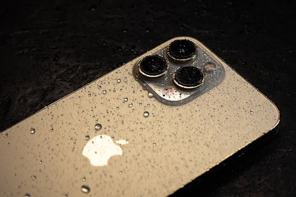 KYIV, UKRAINE - 20 Ekim 2023: Modern akıllı telefon Apple iPhone 15 Pro ve siyah zemin üzerinde su damlaları. Suya dayanıklı modern teknoloji.
