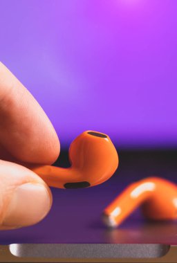 Yaklaş, Orange Wireless Bluetooth Kulaklıklar adamın elinde. Modern Stereo Kulaklık, Spor Kulaklık.