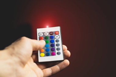 Adam Atmosfer Neon ışığını uzaktan kumandayla ayarlıyor ve kırmızı rengi açıyor. Renkli RGB ampulü. LED Çokrenkli Lump. Ev Işıklandırması. Bloglama ve iş dünyası modern havalı ışıklandırma.