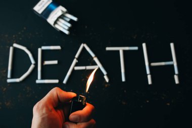 Sigaradan ölüm işareti. Tehlikeli bir alışkanlık. Sağlığa zararlı. Adamın elinde çakmak var..