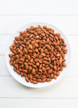 Badem tabakta yatıyor. Sağlıklı yiyecekler. Vejetaryen konsepti. Yaşam tarzı. Fındık arka planı. Boşluğu kopyala.