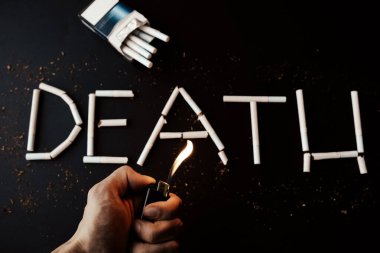 Sigaradan ölüm işareti. Tehlikeli bir alışkanlık. Sağlığa zararlı. Adamın elinde çakmak var..