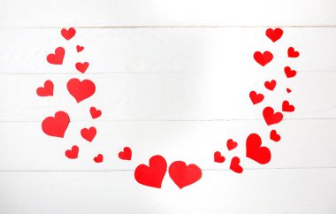 Beyaz ahşap arka planda küçük kırmızı kağıt kalpler. Sevgililer Günü konsepti. Aşk ve romantik fotoğraf. Tatil için kartpostal. Boşluğu kopyala.