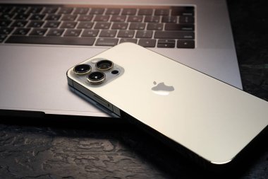 KYIV, UKRAINE - 20 Ekim 2023: Modern akıllı telefon Apple iPhone 15 Pro ve Apple Macbook Pro laptop. Cupertino teknoloji aletleri. Marka logosu adı.