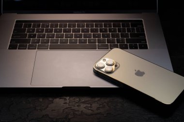 KYIV, UKRAINE - 20 Ekim 2023: Modern akıllı telefon Apple iPhone 15 Pro ve Apple Macbook Pro laptop. Cupertino teknoloji aletleri. Marka logosu adı.