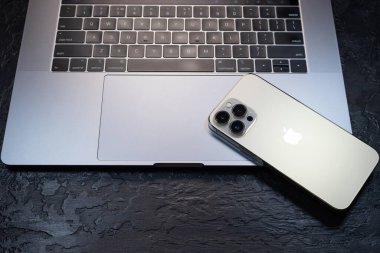 KYIV, UKRAINE - 20 Ekim 2023: Modern akıllı telefon Apple iPhone 15 Pro ve Apple Macbook Pro laptop. Cupertino teknoloji aletleri. Marka logosu adı.