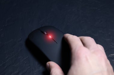 Siyah arka planda erkek eli olan siyah kablosuz minimalist fare. Modern teknoloji aygıtı.